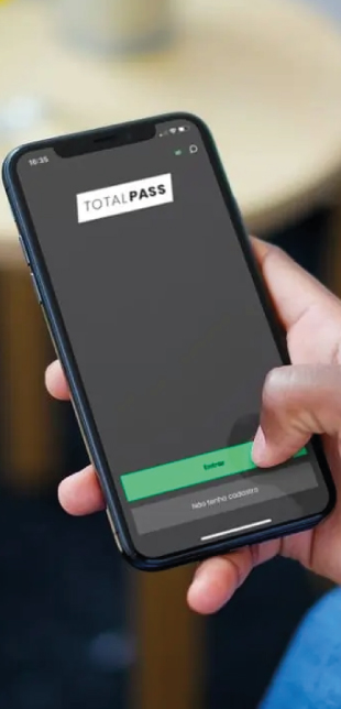 Mão segurando um smartphone acessando o app da TotalPass